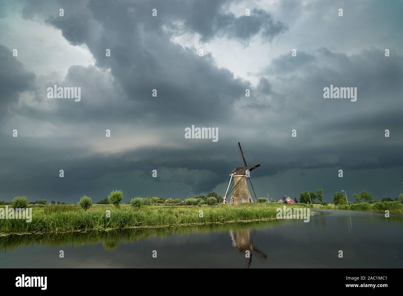 Classic dutch windmill with a stormy sky in the background. Shelfcloud of a severe thunderstorm over the wide open landscape of Holland. Stock Photo