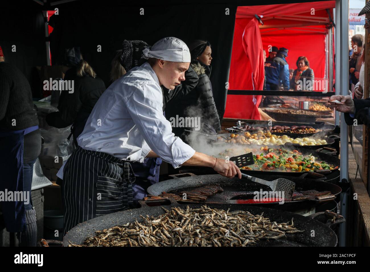 Young chef frying vendaces at Baltic Herring Fair in Helsinki Market Square, Finland Stock Photo