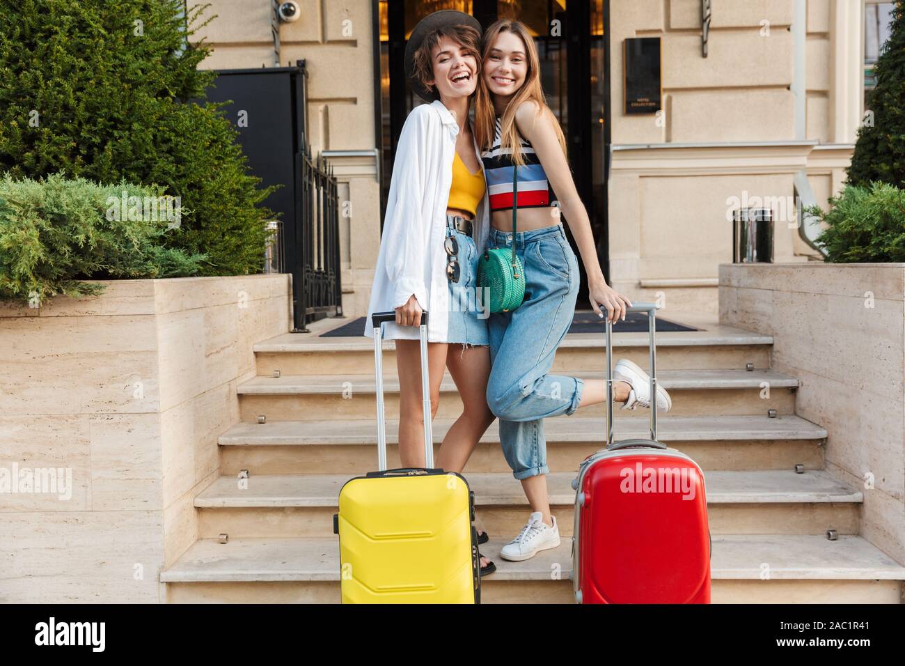 Photo of two adorable tourist women smiling and standing on hotel ...
