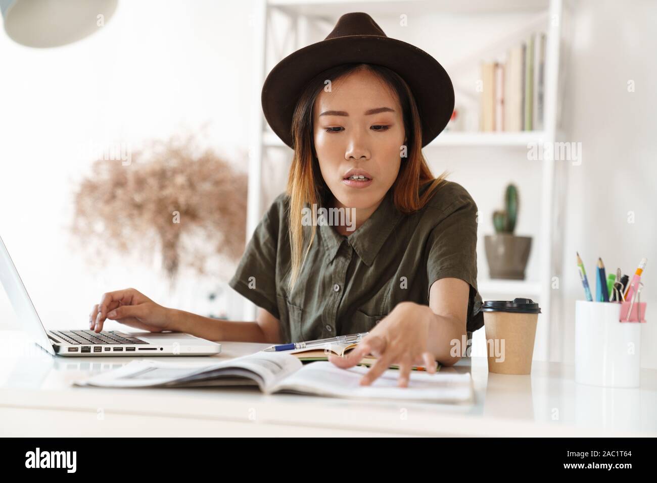 Image of a pretty concentrated young asian woman sit in office using ...