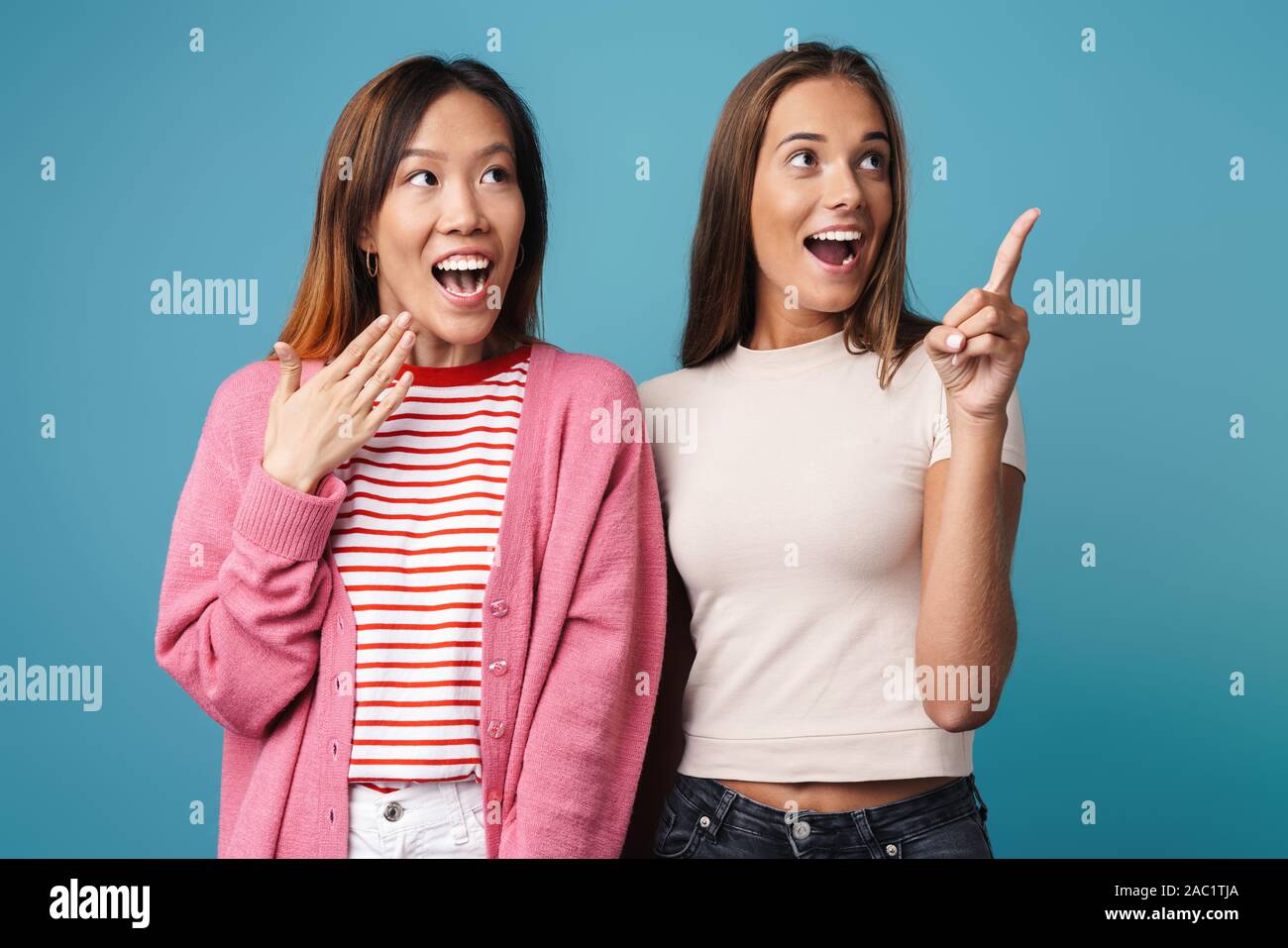Portrait of multinational amazed women looking and pointing finger ...