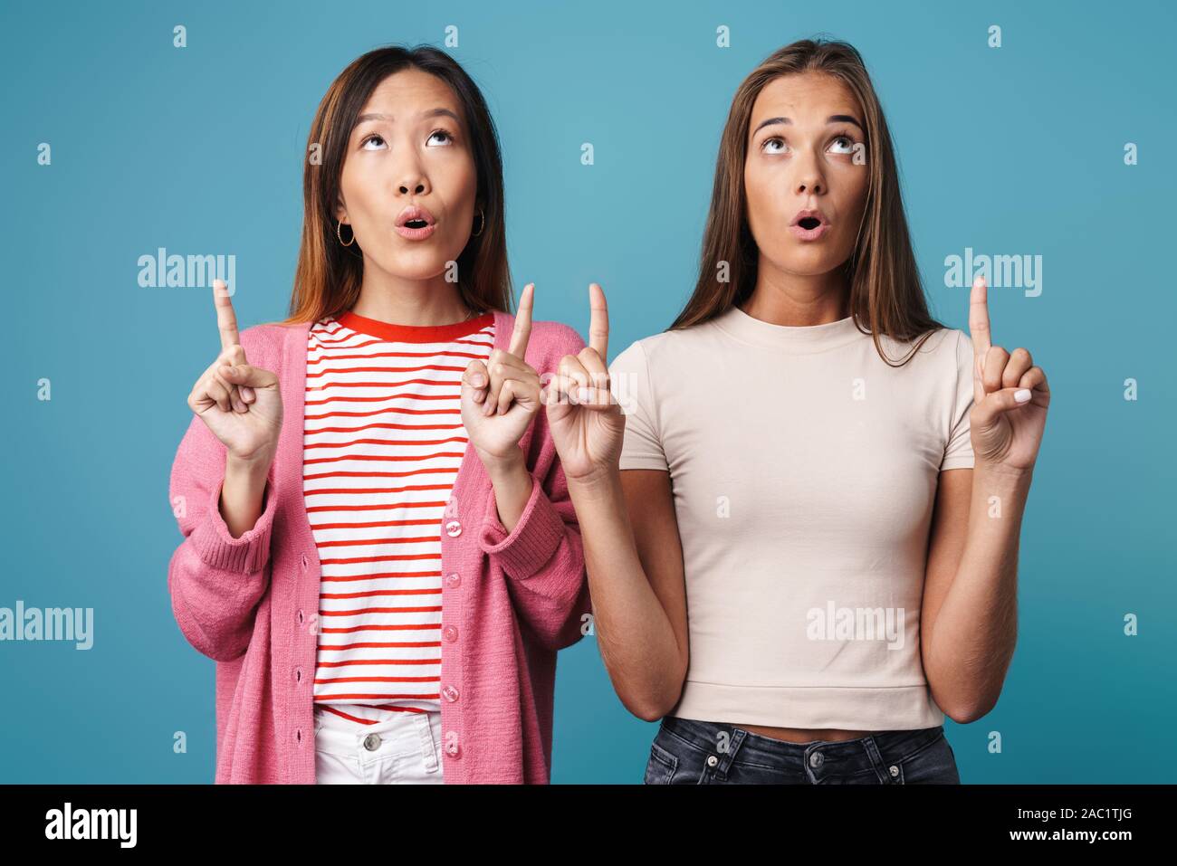 Portrait of multinational shocked women looking and pointing fingers ...