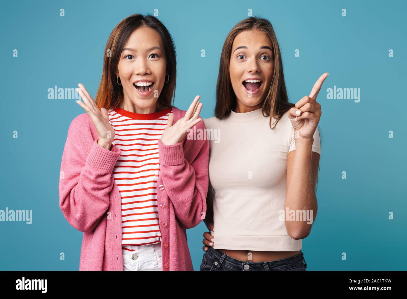 Portrait of multinational excited women looking at camera and pointing ...