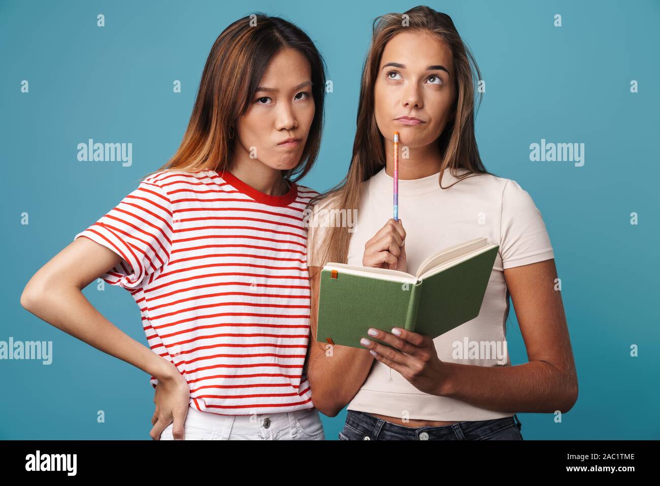 Portrait of multinational serious women holding exercise book and ...