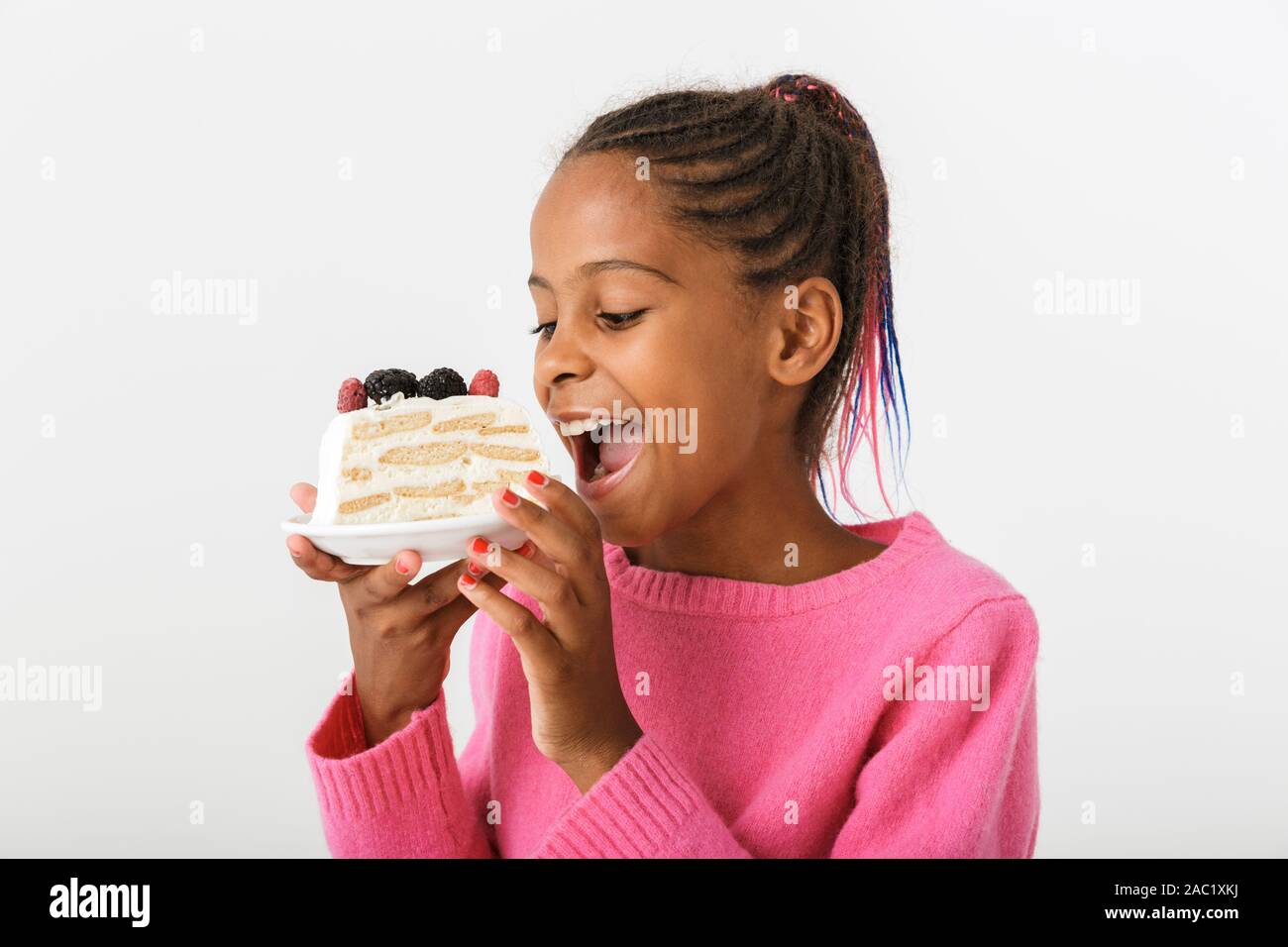 Image of happy african american girl holding and eating piece of torte isolated over white background Stock Photo