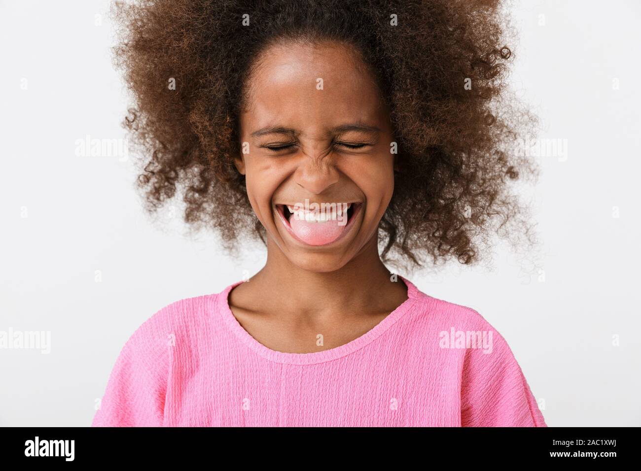 Cheerful funny little african girl wearing pink blouse standing isolated  over white background, grimacing, sticking her tongue out Stock Photo -  Alamy