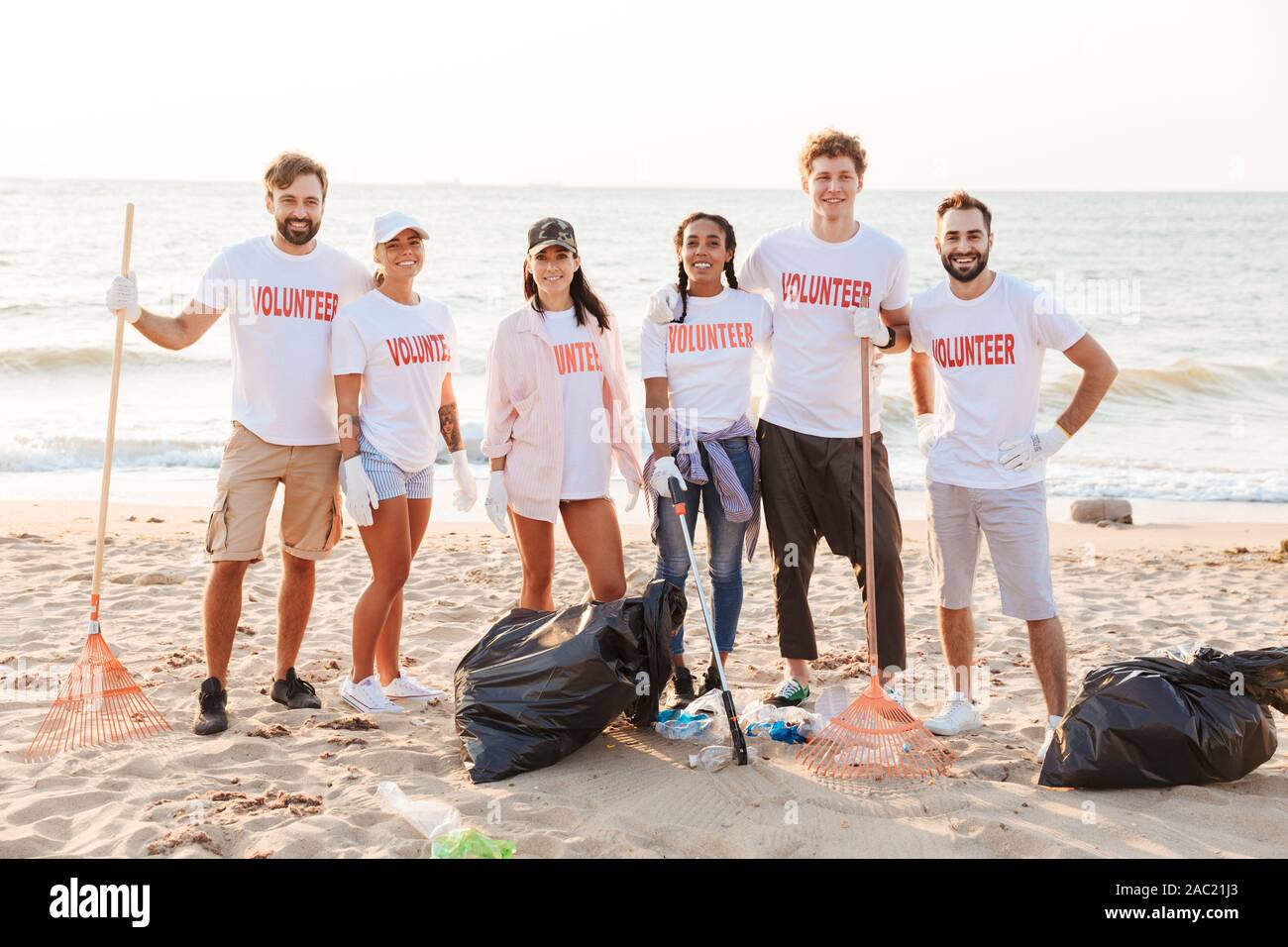 Image of happy multinational voluntary workers cleaning beach from