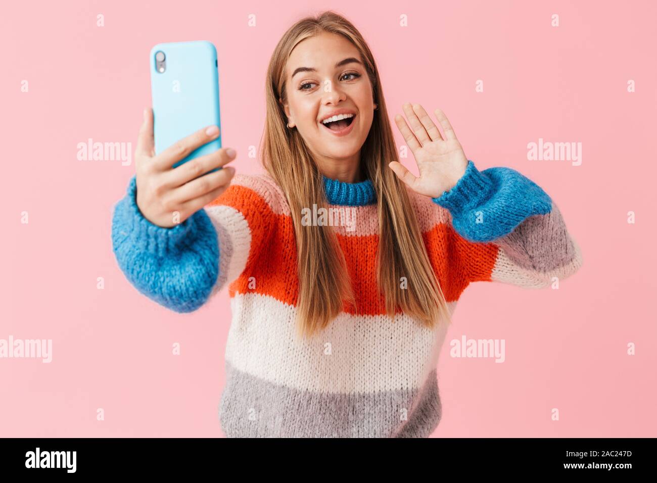 Happy young girl wearing sweater taking a selfie while standing ...
