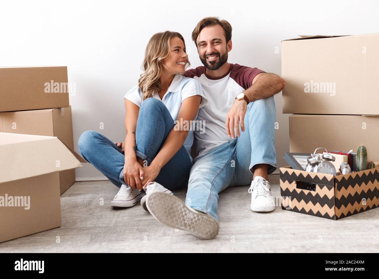 Photo of laughing couple in casual clothing hugging while sitting near ...