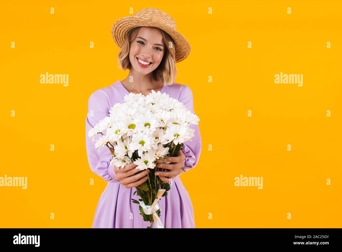 Image of content woman in elegant dress and straw hat holding flowers ...