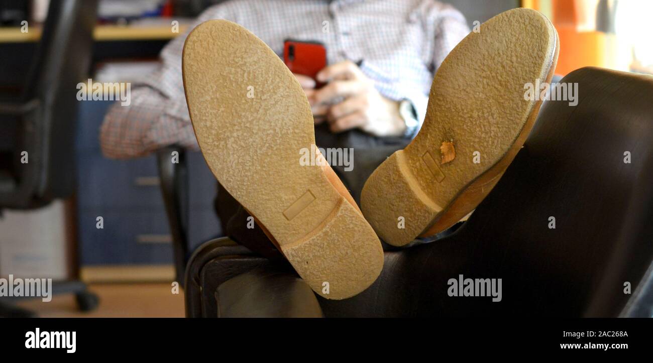 The young man put his feet on chair , sprawled on antoher chair surfing