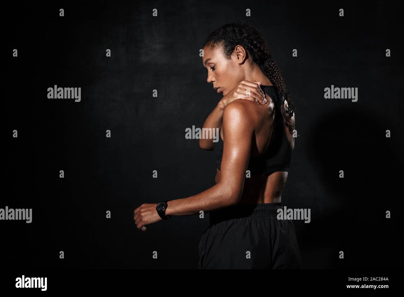 Image from back of feminine african american woman in sportswear standing  isolated over black background Stock Photo - Alamy