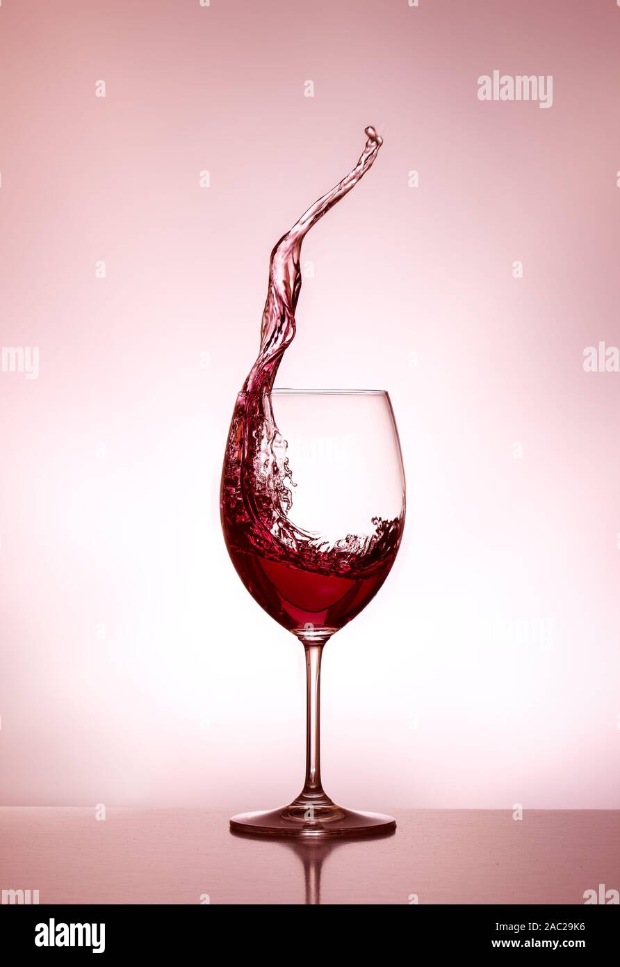 Glass of red wine - the glass is half full - the glass is half empty - splashing wine - spilling wine Stock Photo