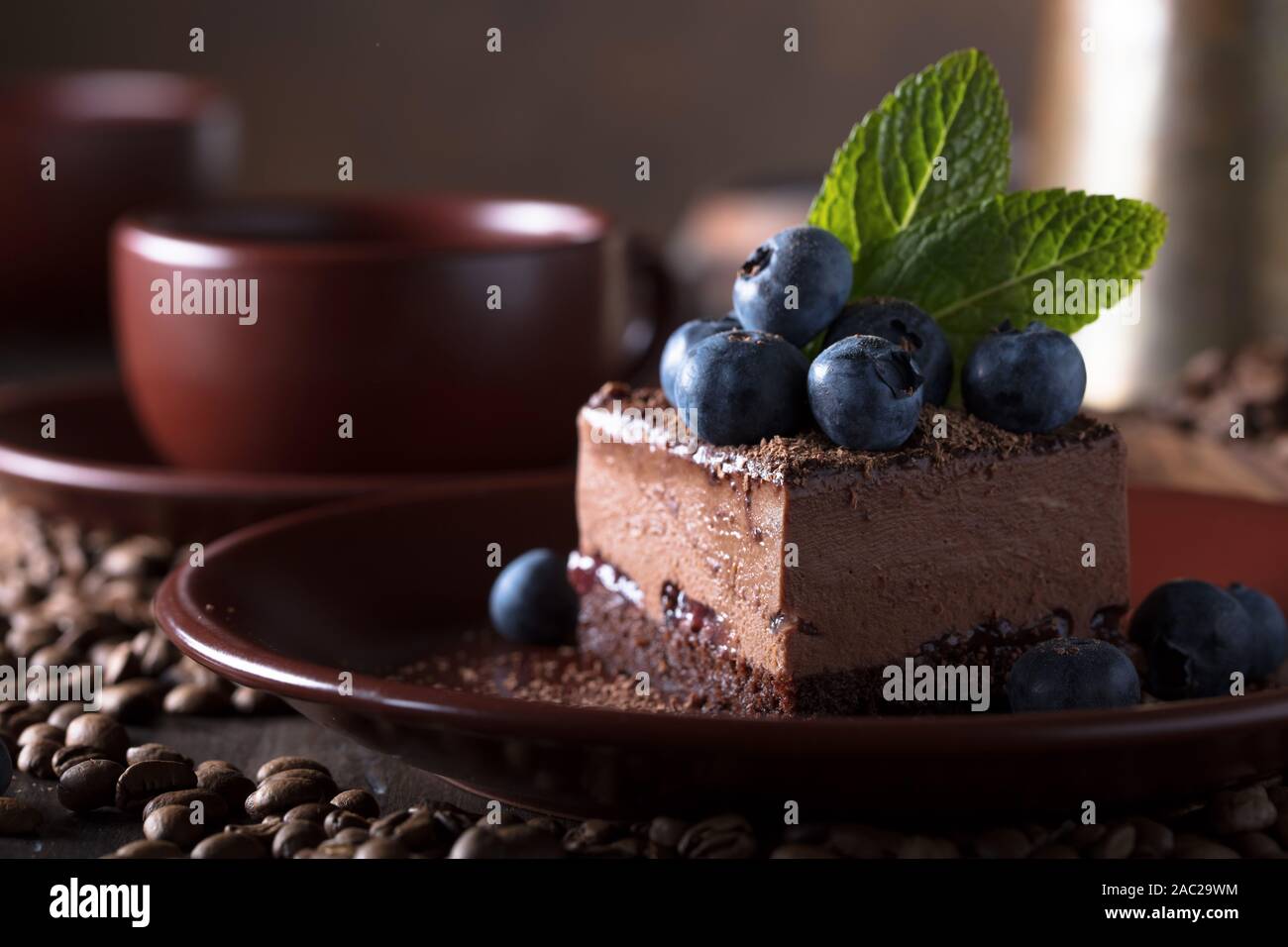 Chocolate cake with blueberries and mint on a brown plate Stock Photo ...