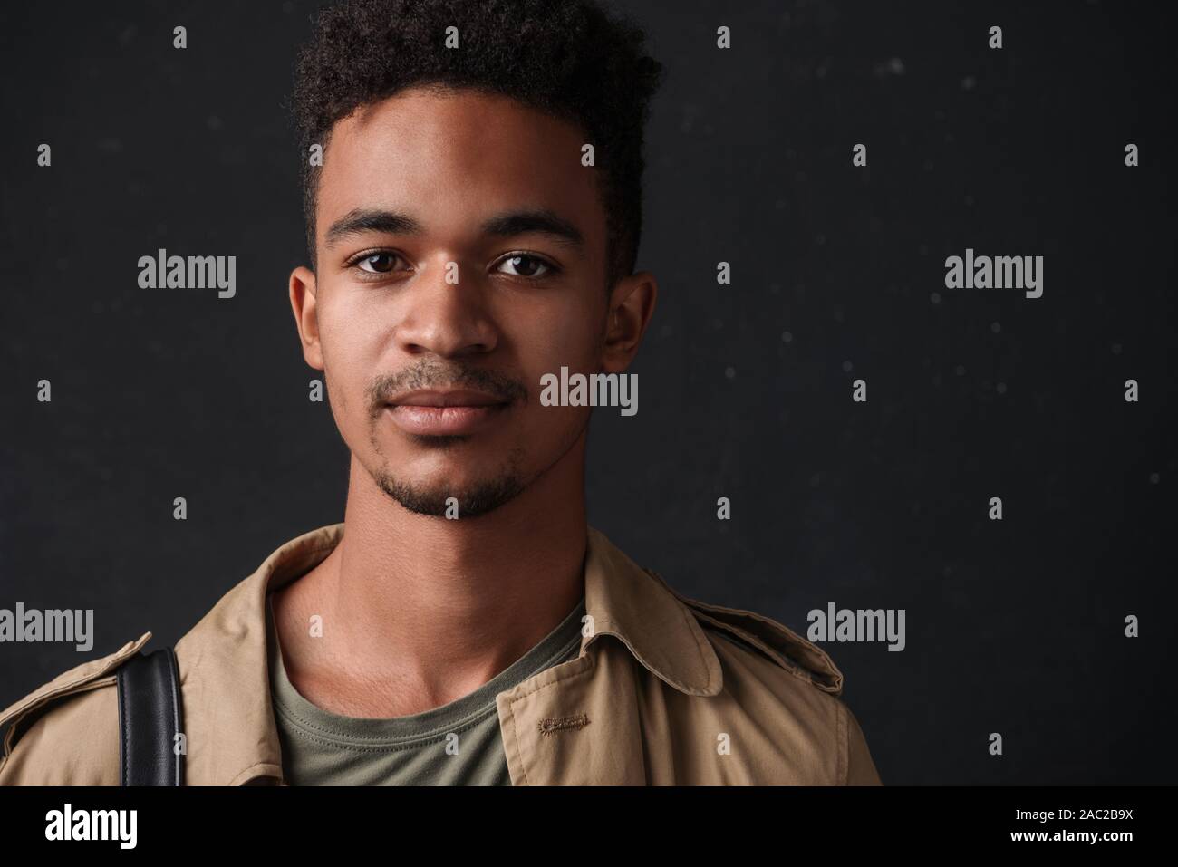 Image of masculine african american guy in coat posing and looking at camera isolated over black background Stock Photo