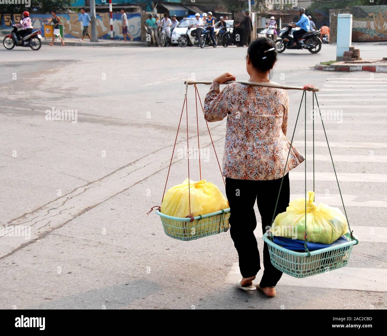 Vietnamese woman with the traditional basket crossing the streets of