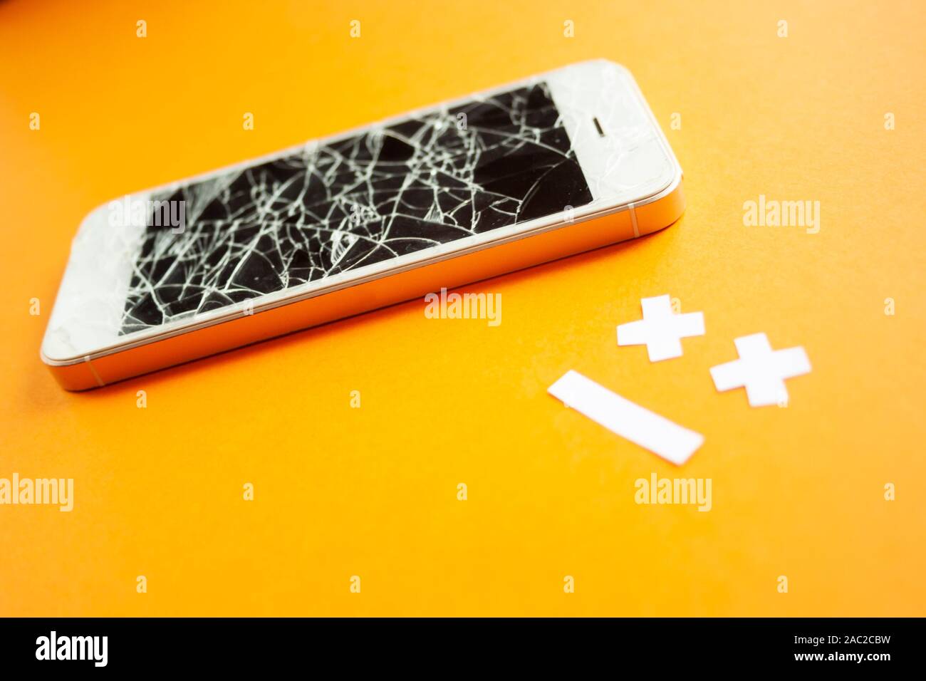 Broken smartphone with cracked destroyed screen on orange background
