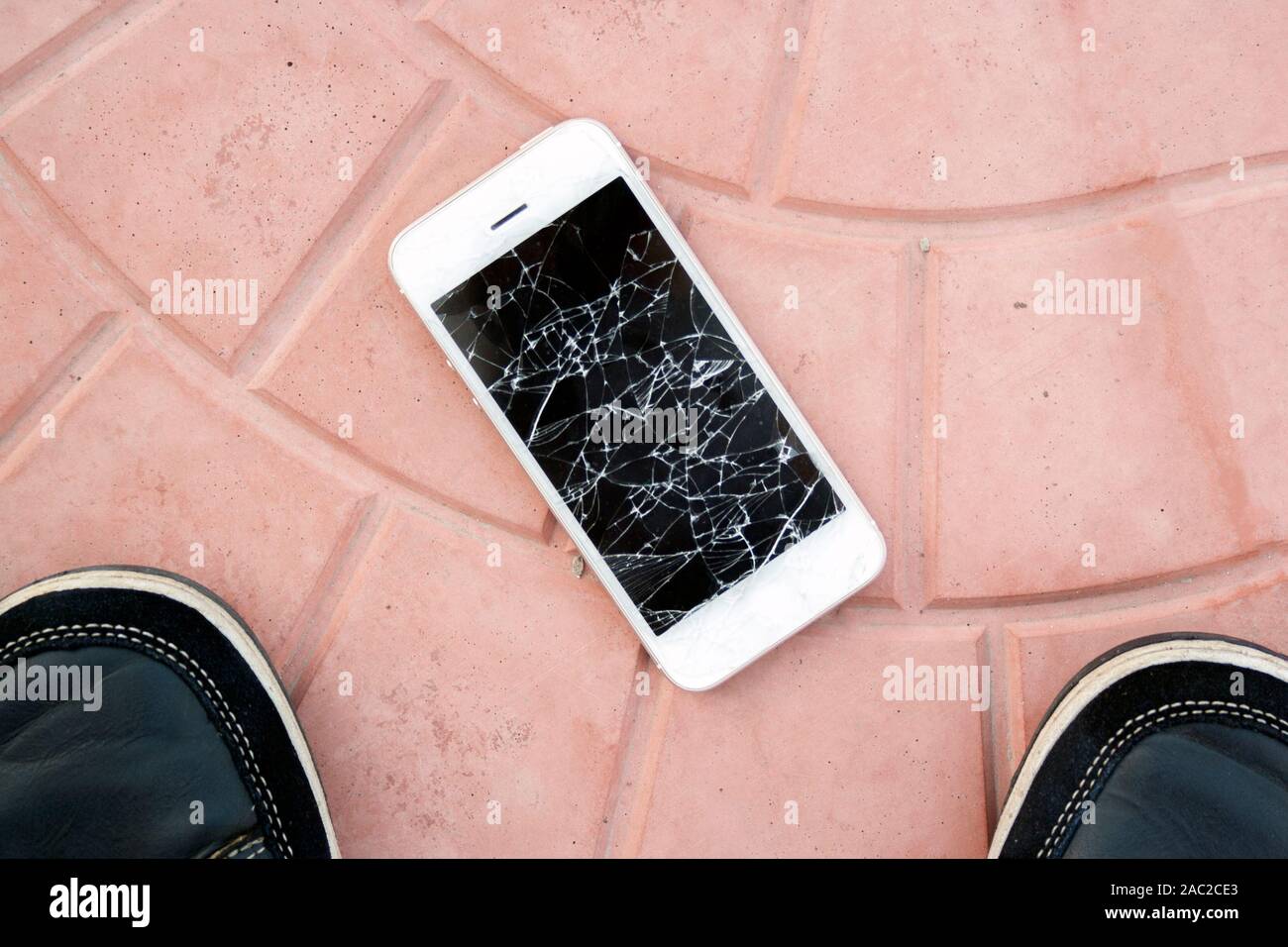 broken smartphone screen. Feet and smartphone with a broken screen on