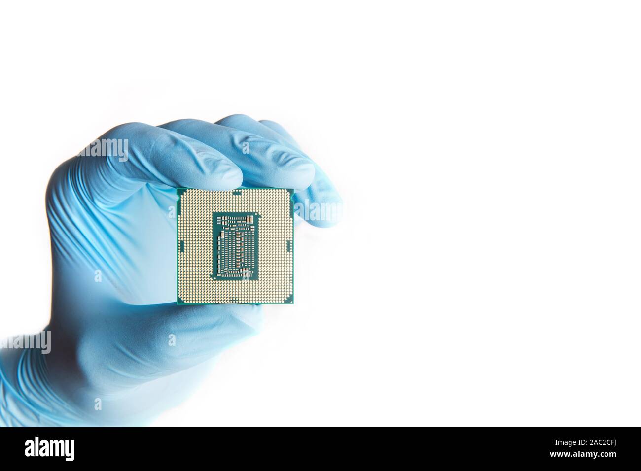 Hand in blue gloves holds micro processor cpu, close up. White background. Stock Photo