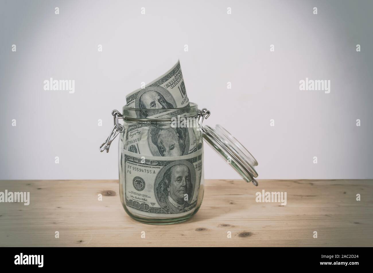 Dollar bills in glass jar on wooden table. Saving money concept. Stock Photo