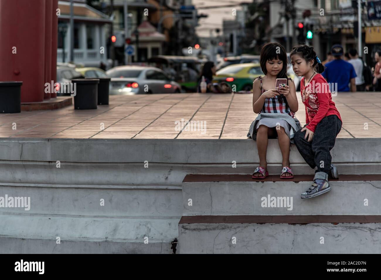 Bangkok, Thailand - Nov 23, 2019 : Two girls siting down and looking on the cell photo at The Giant Swing (Sao Ching Cha). Stock Photo