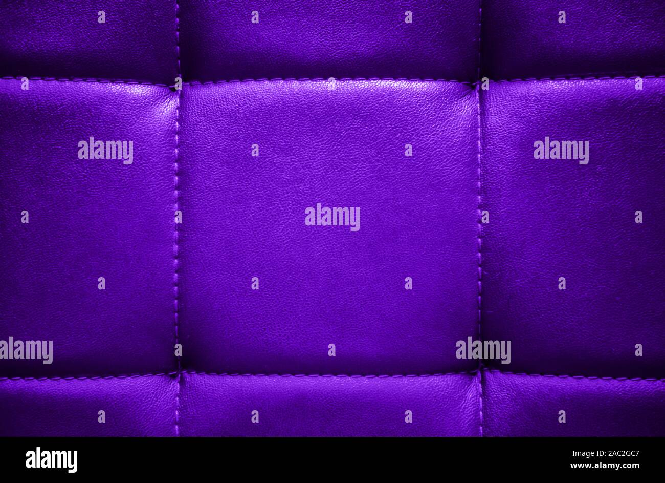 Shiny electric purple artificial textured leather stitched with thread. Close-up of sofa surface. View from directly above. Highly detailed background Stock Photo