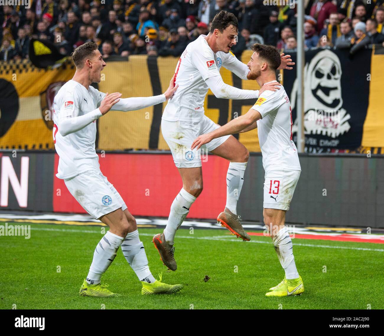 30 November 2019, Saxony, Dresden: Soccer: 2nd Bundesliga, SG Dynamo Dresden - Holstein Kiel, 15th matchday, in the Rudolf Harbig Stadium. Kiels Salih Özcan (r) cheers after his goal to 0:2 with Janni-Luca Serra (M) and Phil Neumann. Photo: Robert Michael/dpa-Zentralbild/dpa - IMPORTANT NOTE: In accordance with the requirements of the DFL Deutsche Fußball Liga or the DFB Deutscher Fußball-Bund, it is prohibited to use or have used photographs taken in the stadium and/or the match in the form of sequence images and/or video-like photo sequences. Stock Photo