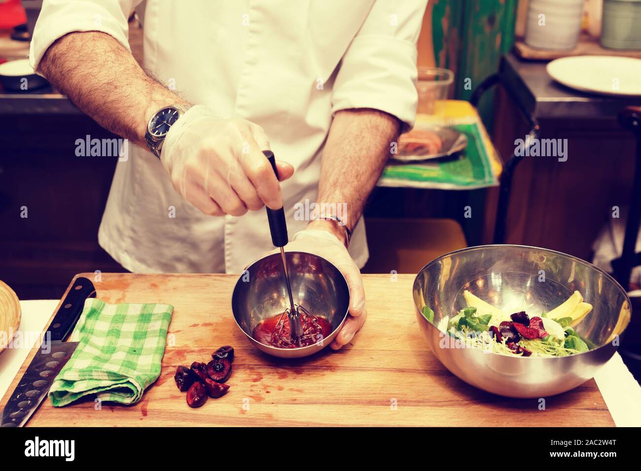 Chef is cooking salad dressing of red berries, oil and vinegar with ...