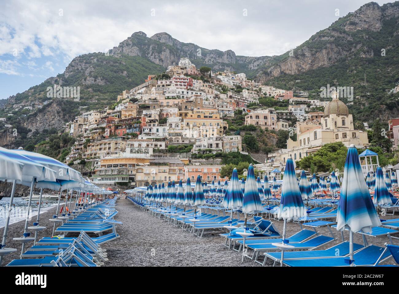 Positano beach with umbrella beds with Amalfi crags in background Stock