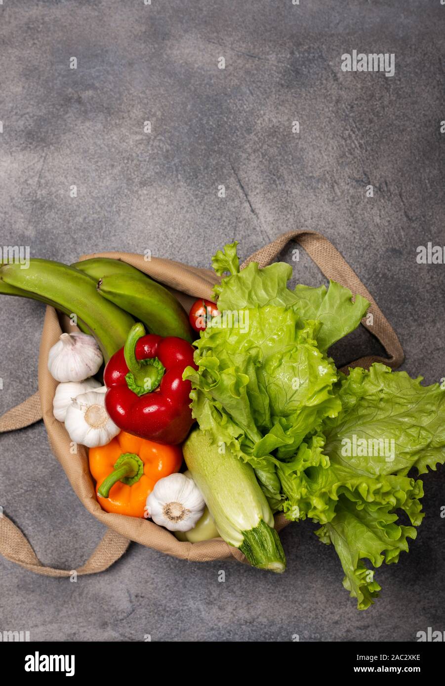 Fabric eco bag full of organic fresh vegetables and baguette on a dark ...