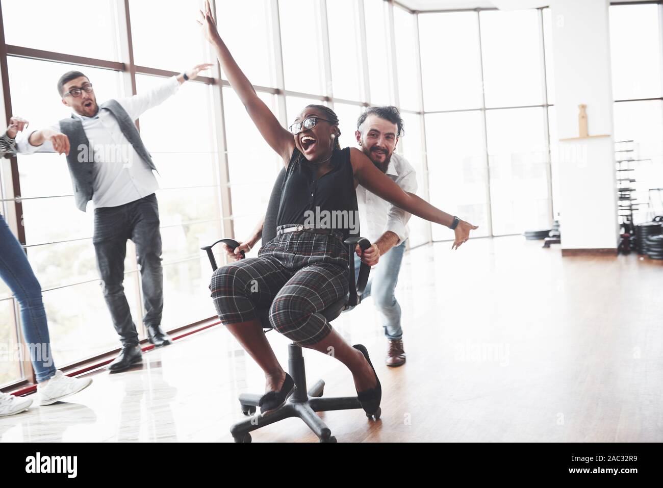 Young people having fun in the spacey office room riding the afro