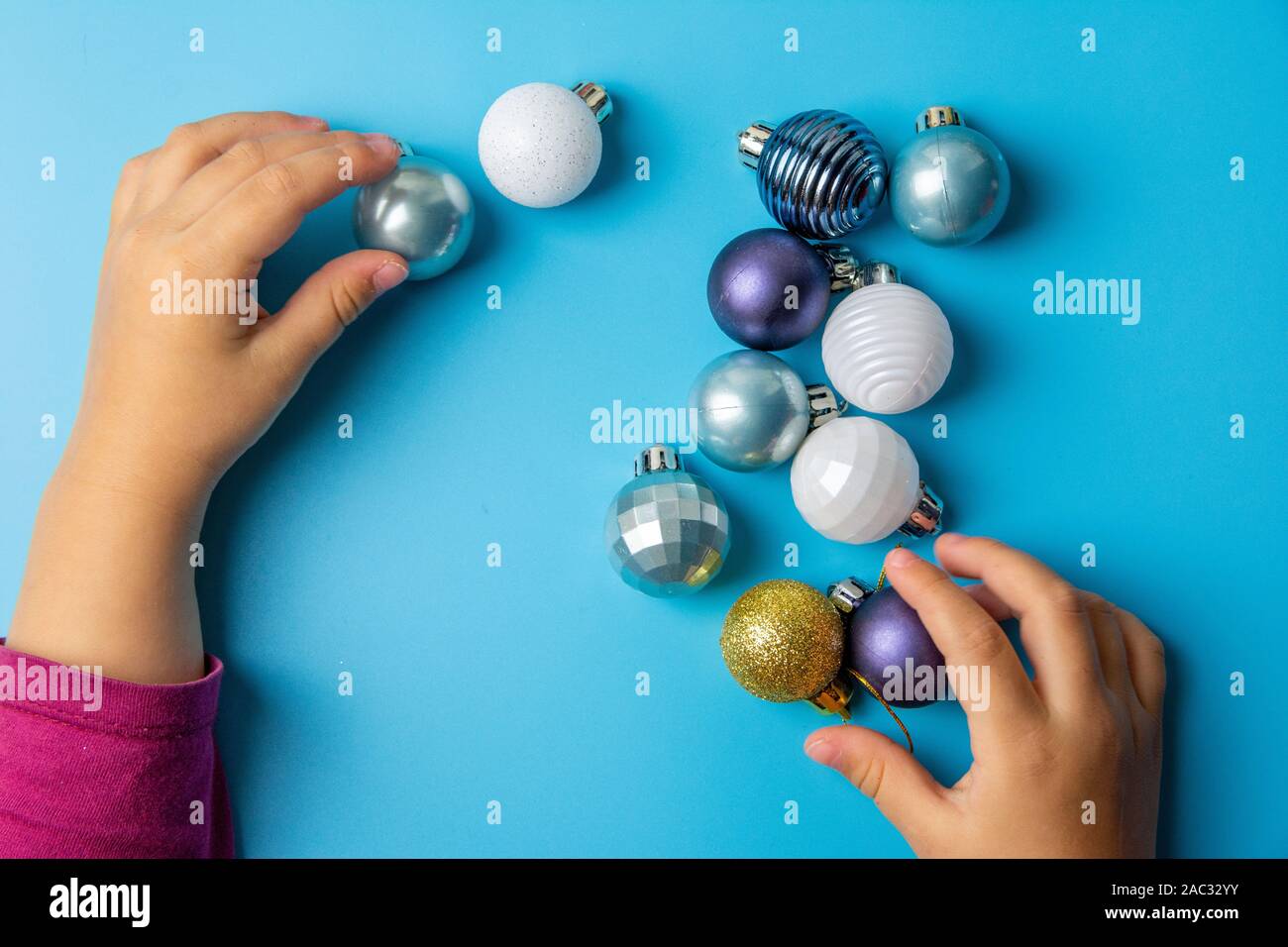 children's pens play with multi-colored Christmas toys on a blue background. Stock Photo