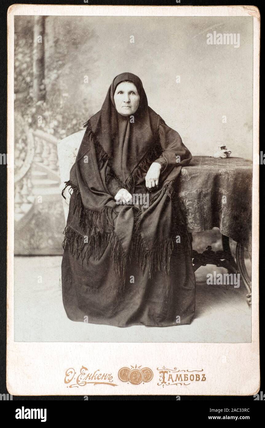 Vintage photo of Russian senior woman sitting near table in photo studio. Photo was taken at beginning of 20th century in Tambov. (from my collection) Stock Photo