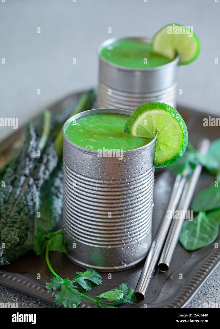 Healthy kale and spinach smoothies served in repurposed metal cans with stainless steel drinking straws Stock Photo