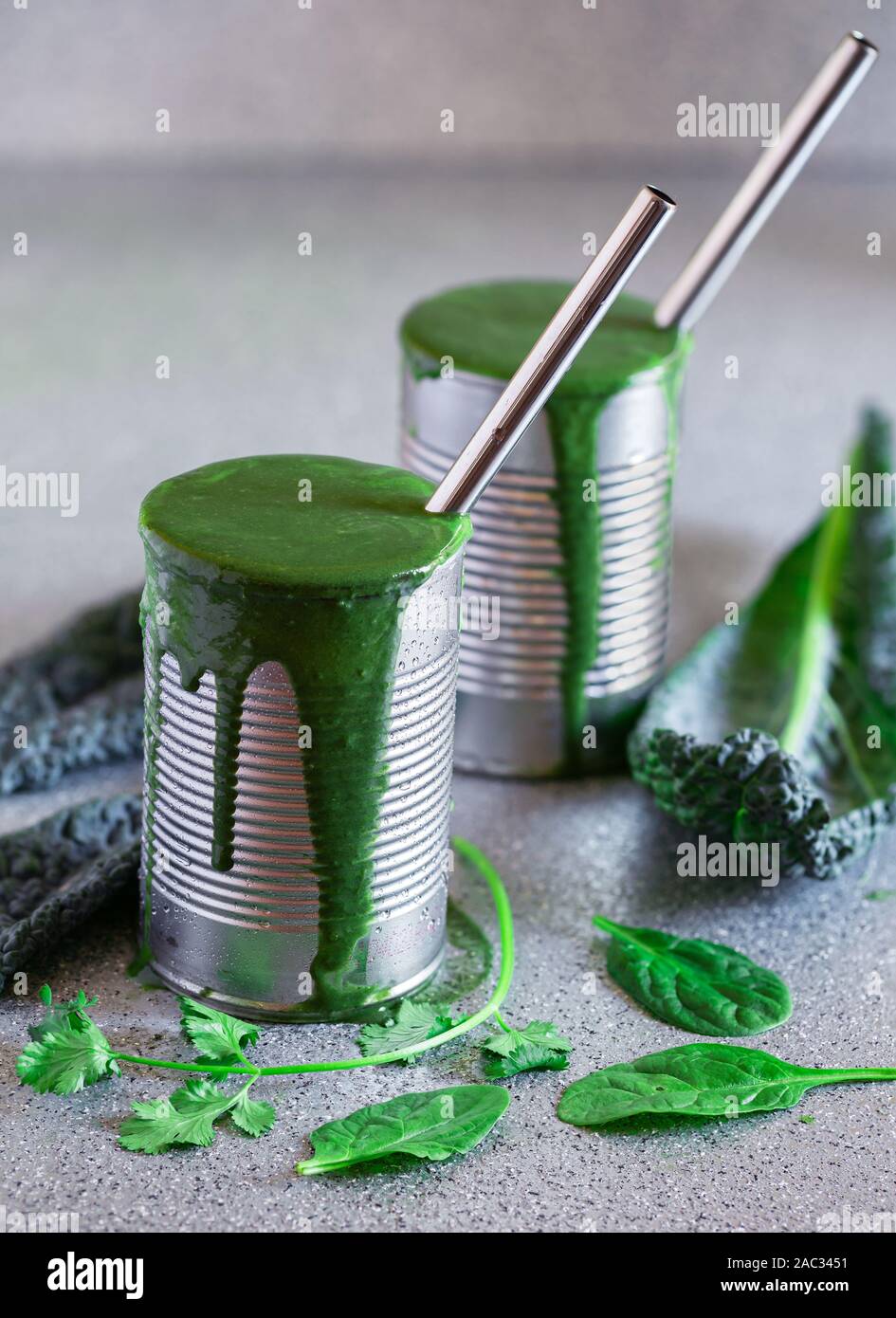 Healthy kale and spinach smoothies served in repurposed metal cans with stainless steel drinking straws Stock Photo