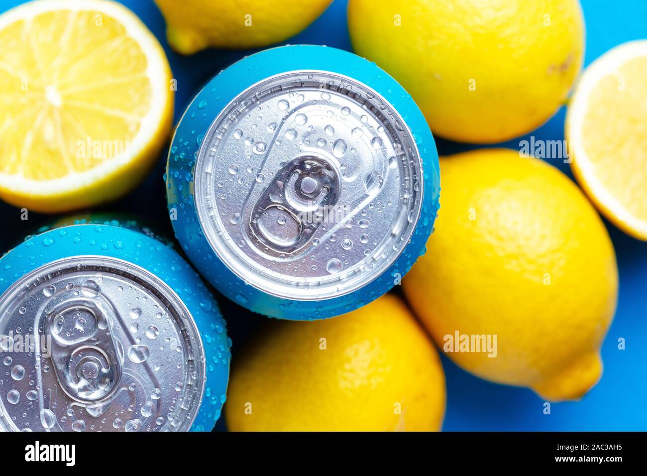 Soda cans and lemons over blue background, Top view, macro shot Stock Photo