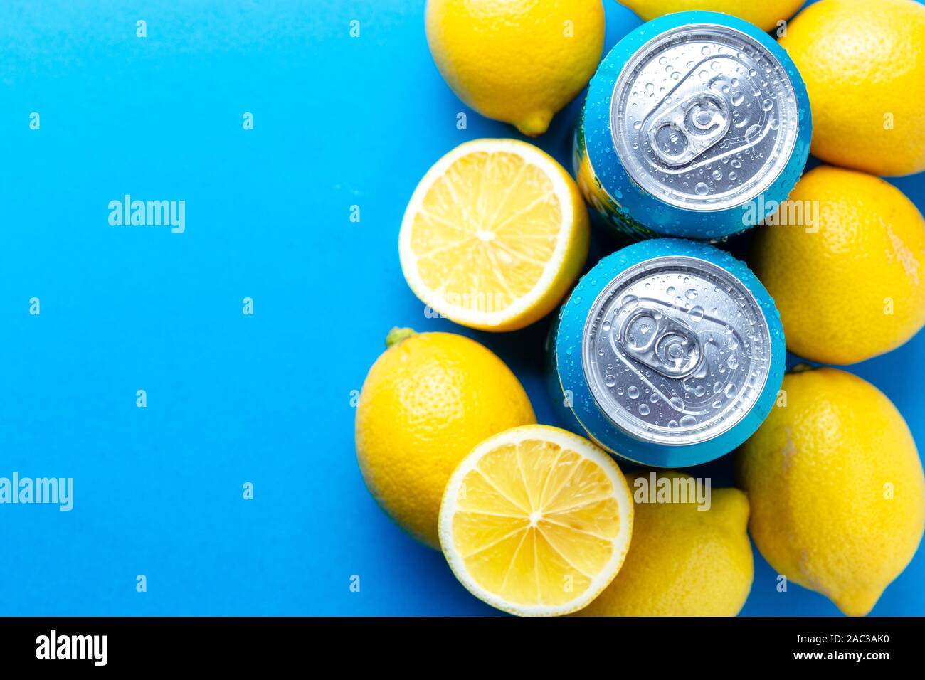 Soda cans with condensation drops and lemons over blue background Stock Photo