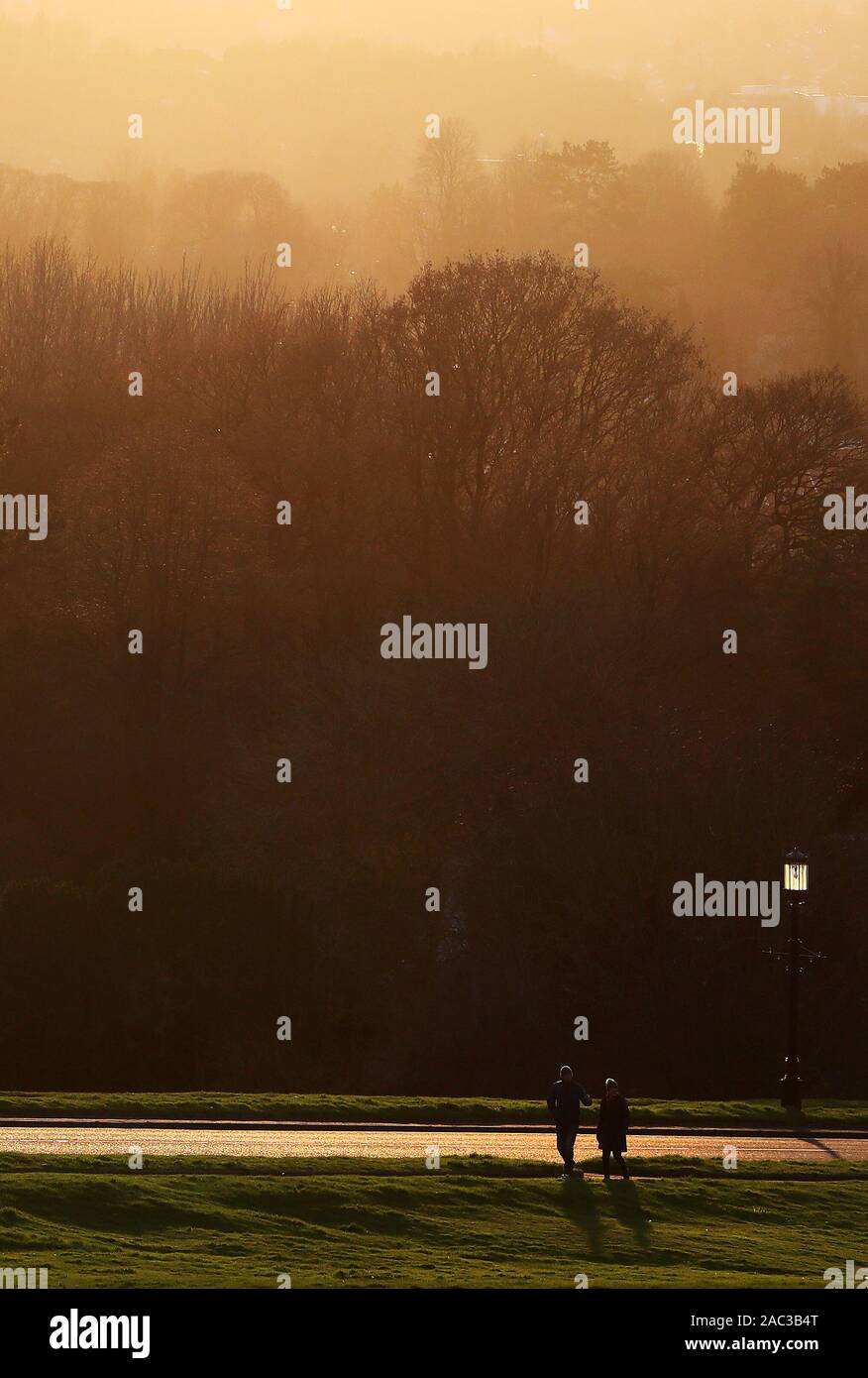 People walk on the grounds of Stormont Estate as the sun sets over Belfast. Stock Photo