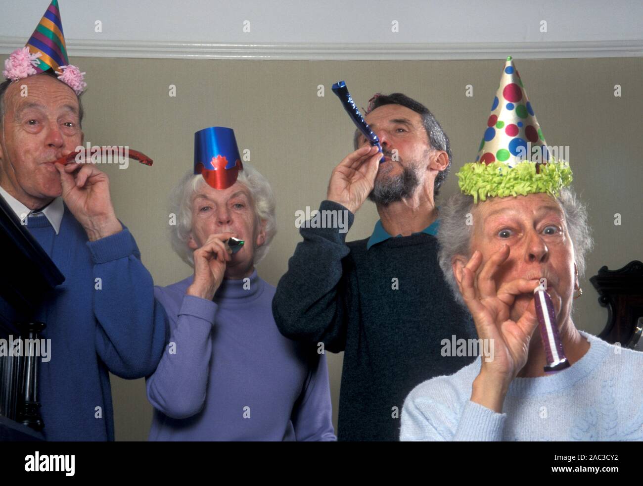 Spirited seniors at a Christmas party blowing party blowers Stock Photo