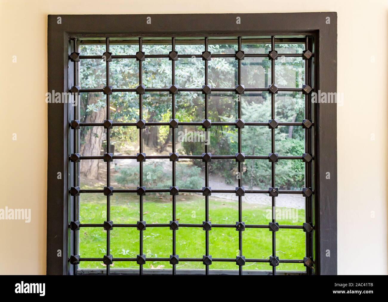 Iron barred home glass window and back to garden green grass Stock Photo