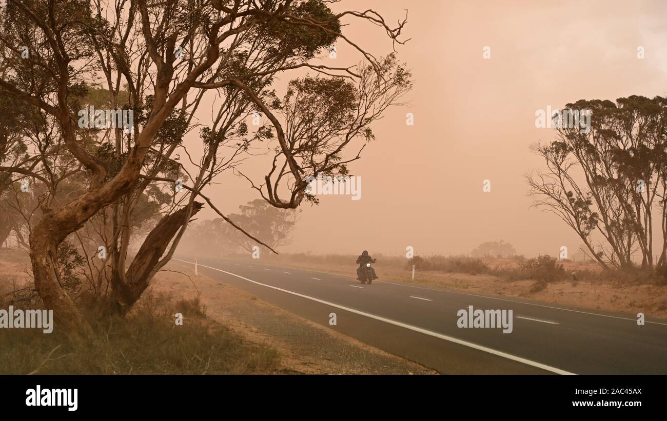 Lone biker rides through severe dust conditions on the Sturt Highway west of Mildura, November 2019. Stock Photo