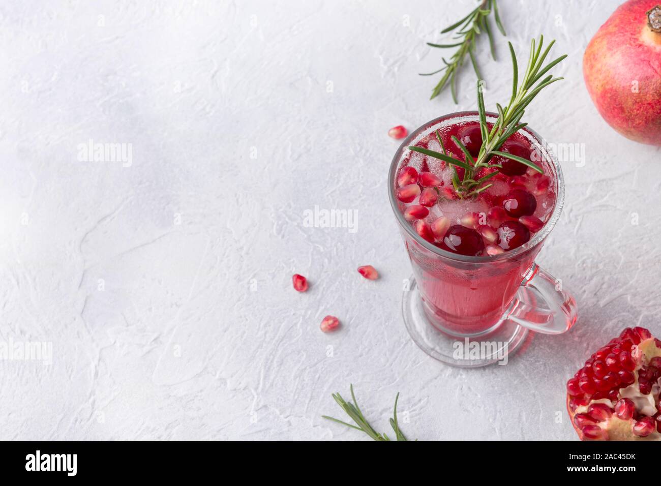 Pomegranate Christmas cocktail with rosemary, cranberry, champagne, club soda on grey concrete table. Xmas drink. View from above. Space for text. Stock Photo