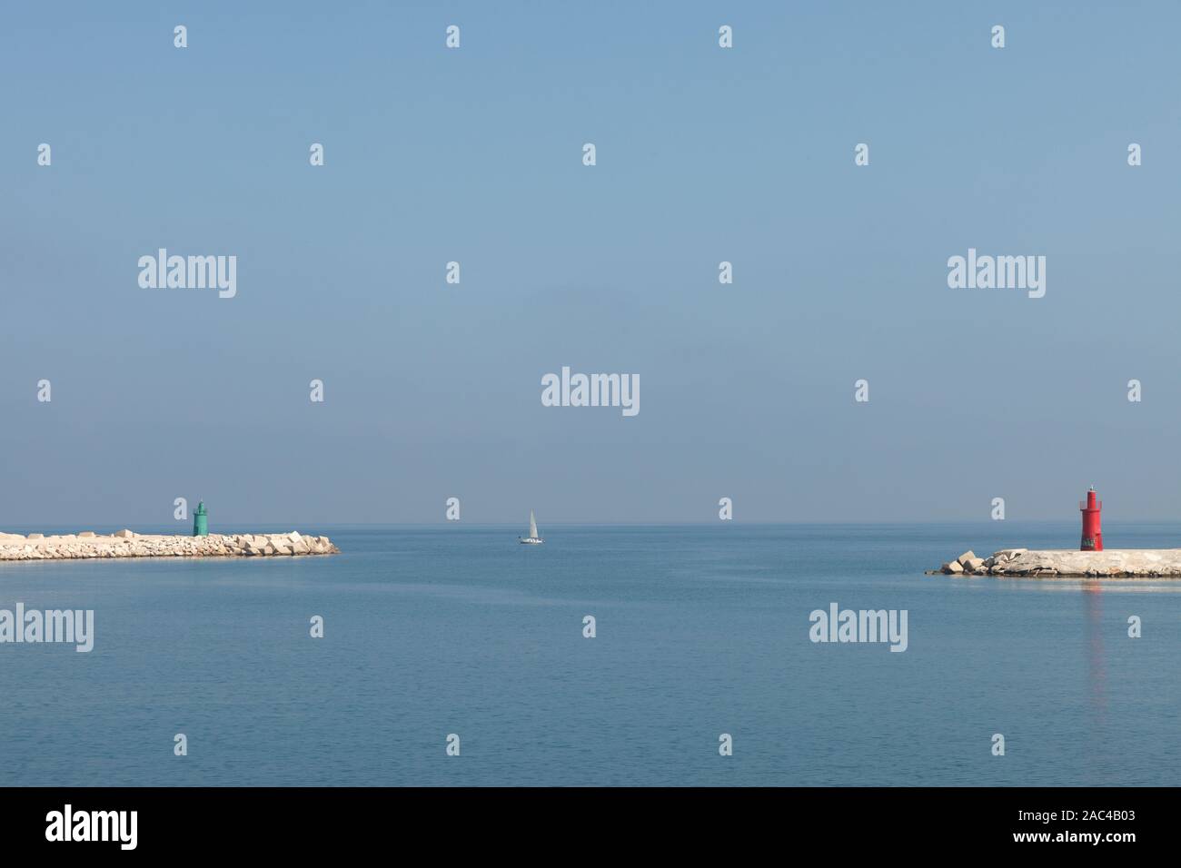 Сalm scene with green and red lighthouse and yacht. Trani, Italy Stock Photo