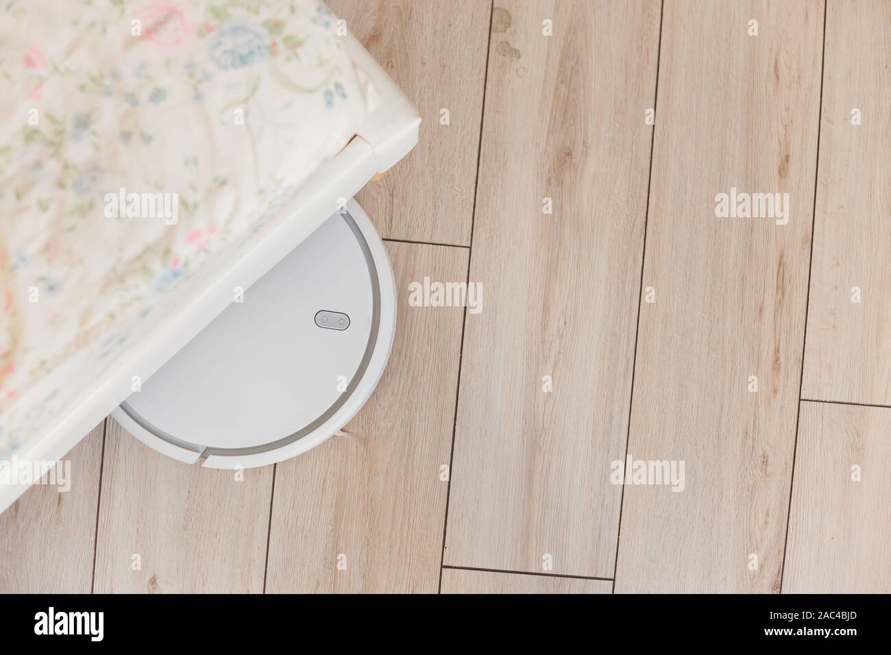 Robot vacuum cleaner vacuuming under the bed. Top view Stock Photo Alamy