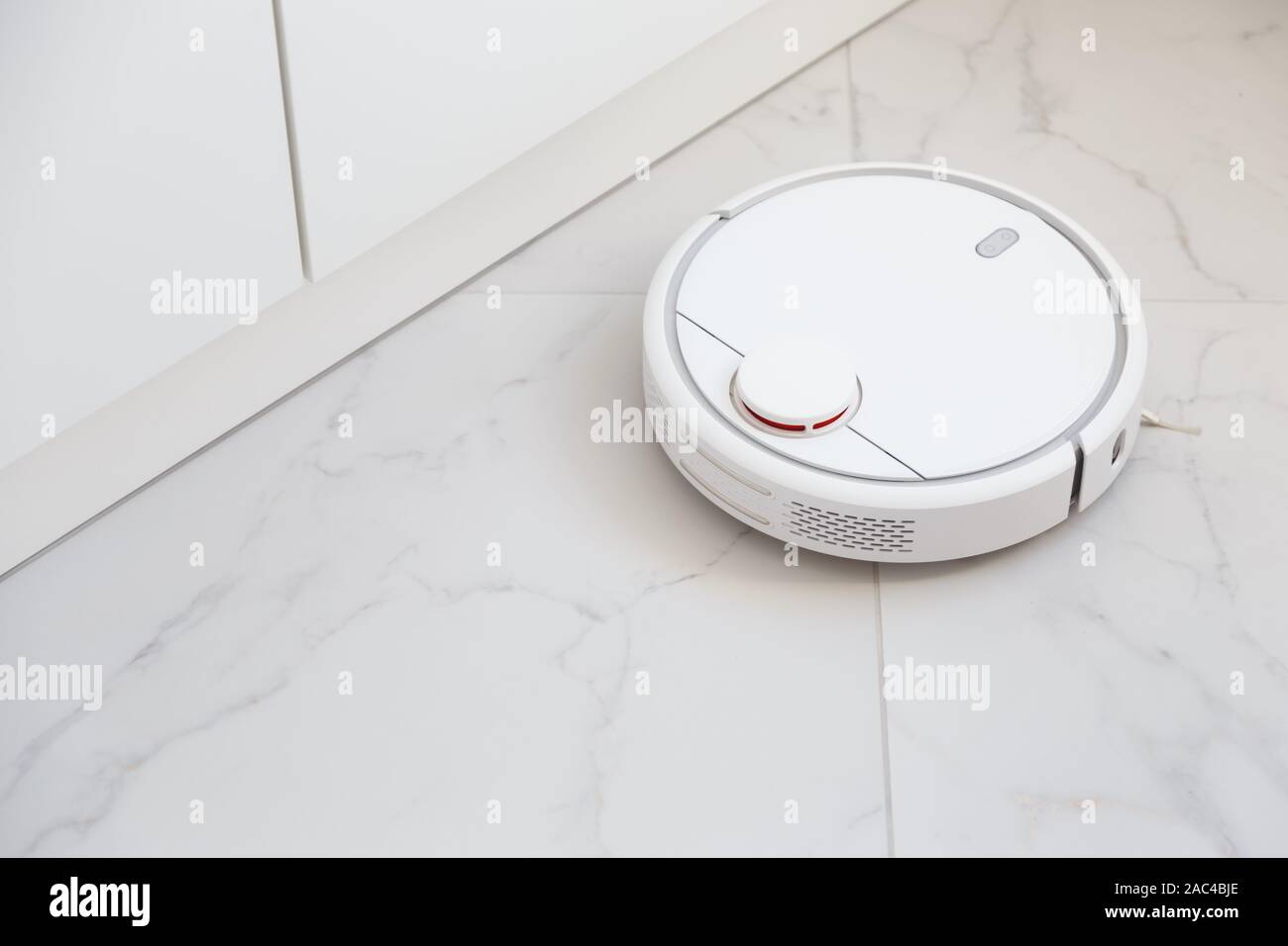 Robot vacuum cleaner vacuuming tiles in room Stock Photo Alamy
