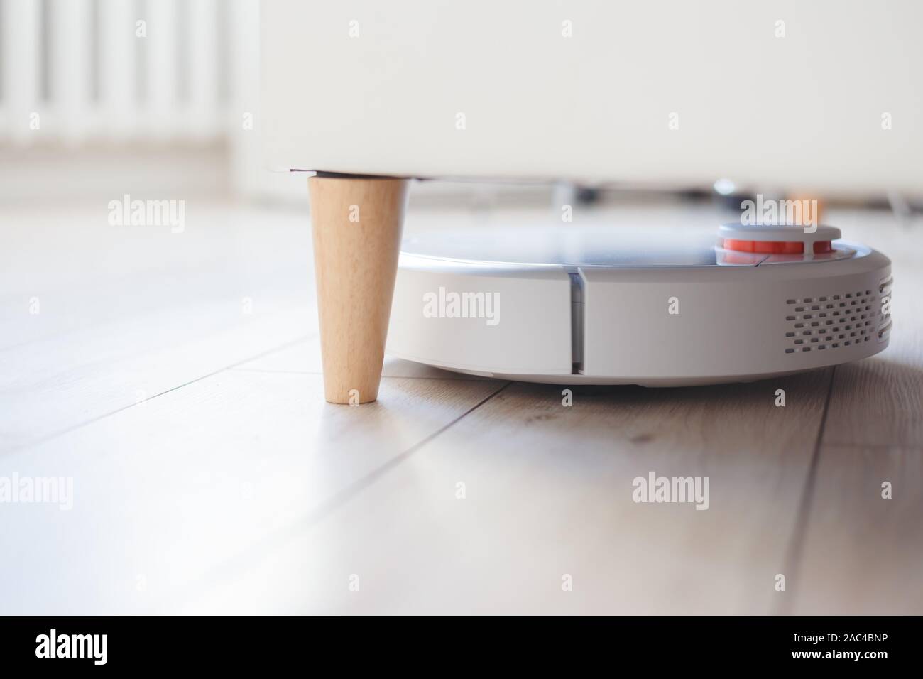 Robot vacuum cleaner vacuuming under the bed Stock Photo