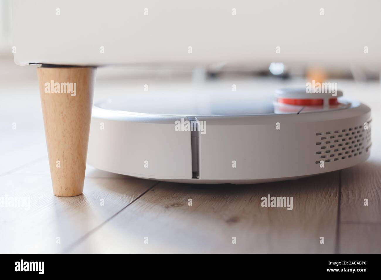 Robot vacuum cleaner vacuuming under the bed Stock Photo