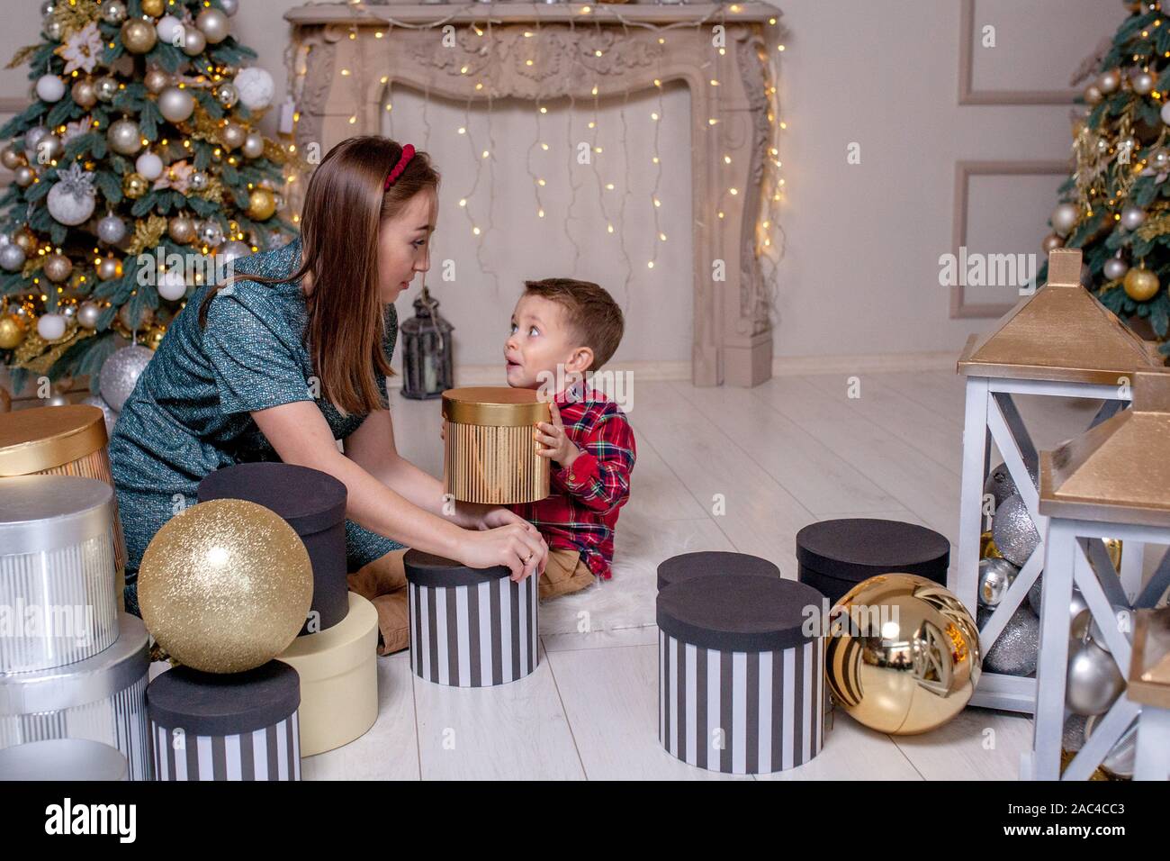 Mother gives Christmas gift to his little son for a New Year. Mom and son  opening Christmas presents Stock Photo - Alamy