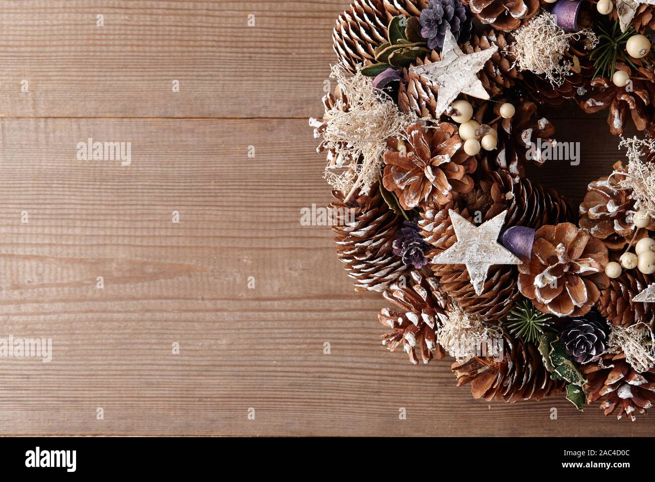 Christmas wreath decorated with pine and fir tree cones on wooden door, close up view Stock Photo