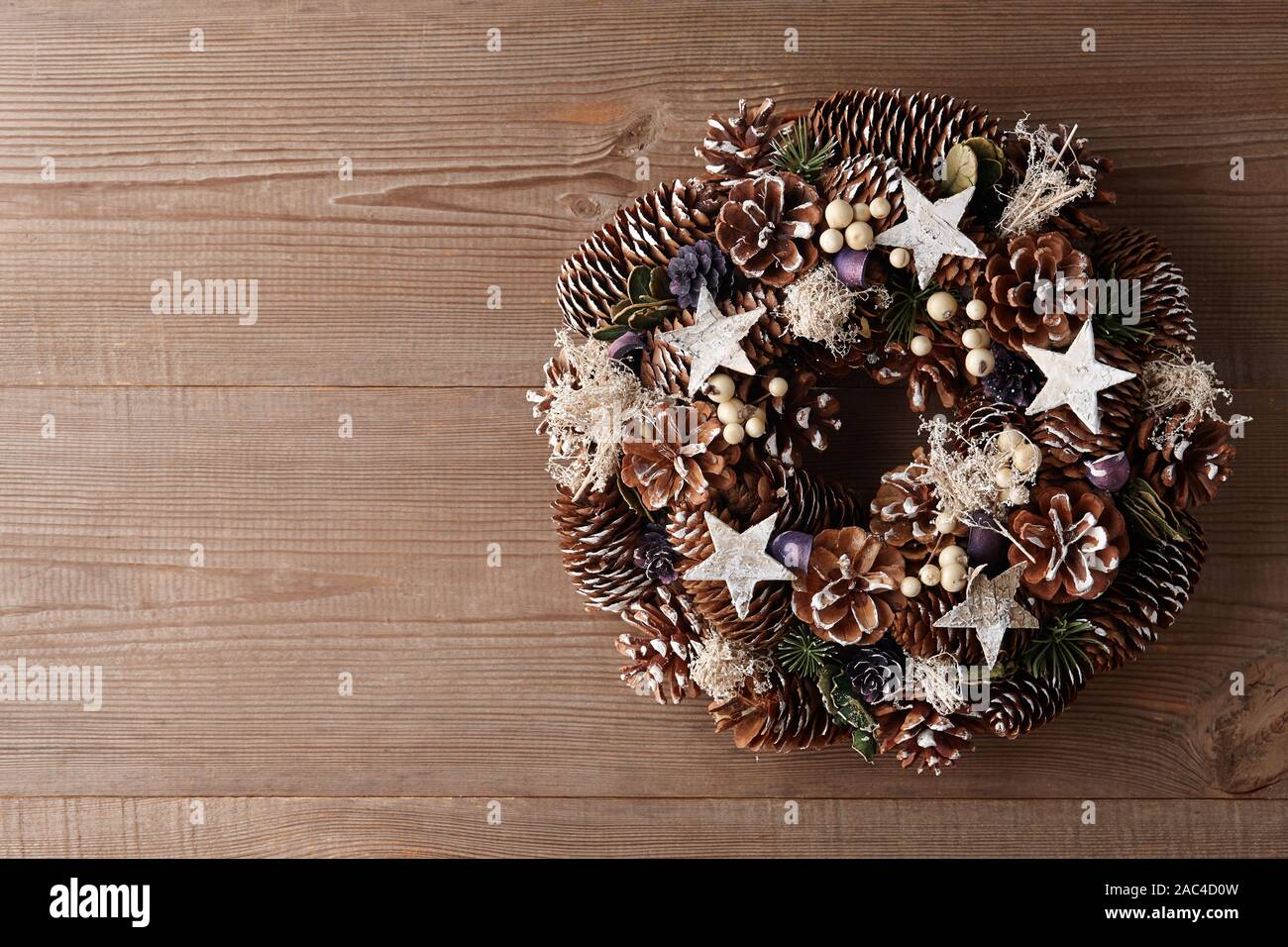 Christmas wreath decorated with pine and fir tree cones on wooden door ...